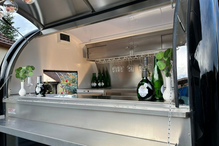 Barwagen mit Flaschen, Gläsern und frischen Kräutern in einer modernen Umgebung.