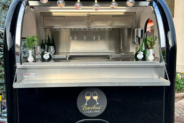 Ein eleganter Getränkewagen mit Gläsern und grünen Pflanzen.